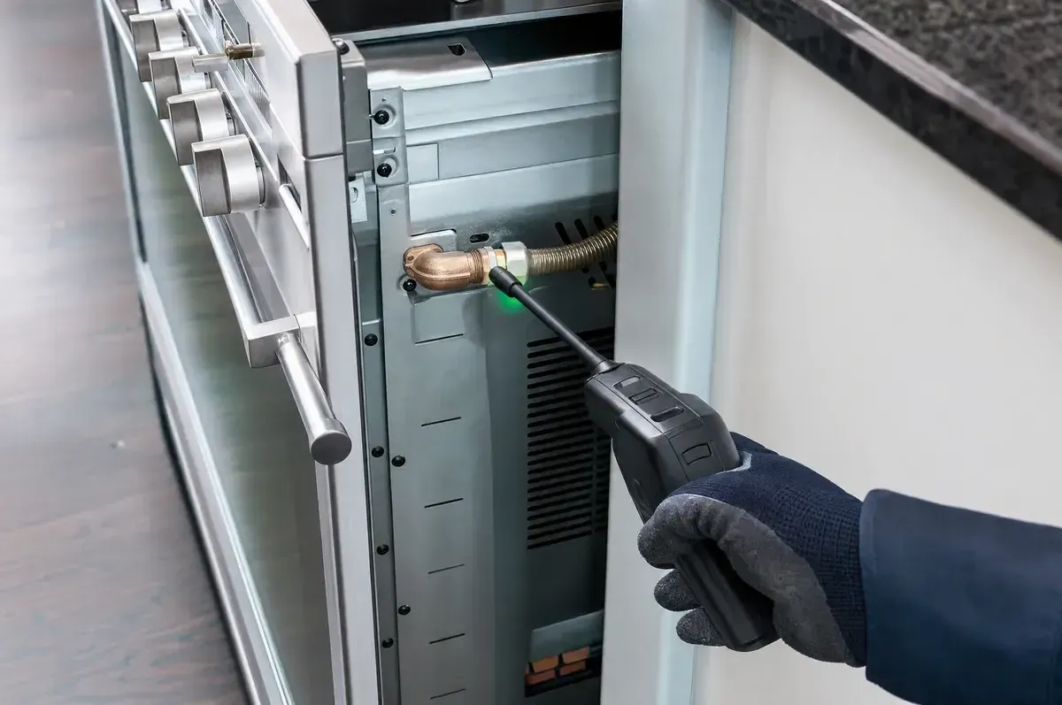 Electronic gas leak detector wand checking an appliance connection